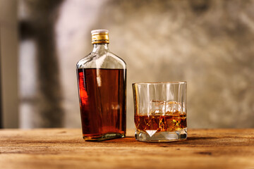 Wiskey in a glass with the ice cubes on the reflective black surface. Bar drinking menu