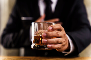 Closeup of executive holding whiskey at wooden desk to illustrate executive privilege concept.