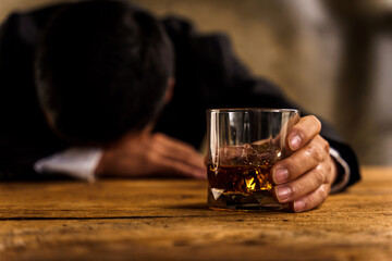 Alcoholism, depressed asian young man sleep on table while drinking alcoholic beverage, holding glass of whiskey alone at night. Treatment of alcohol addiction, suffer abuse problem alcoholism concept