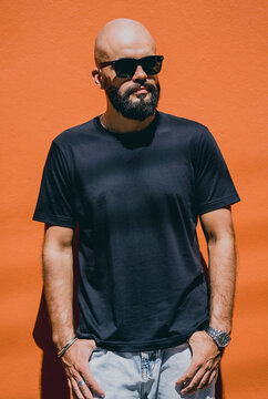 Male model with beard wearing black blank t-shirt on the background of an orange wall