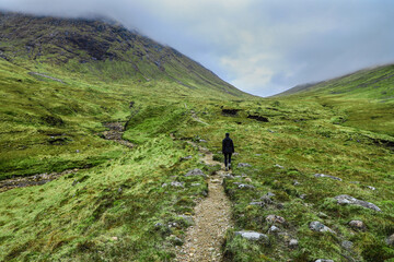 Fototapeta na wymiar Hiker on in the dramatic green valley of Buachaille Etive Beag in the Scottish Highlands
