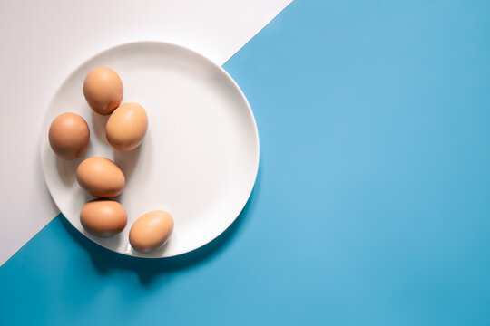 Flat lay, eggs on a white plate on a blue background.