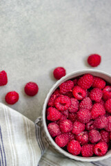 Ripe large raspberries in a ceramic round bowl on a gray background