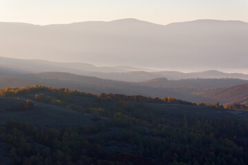 foggy autumn morning. beautiful landscape in mountains at sunrise. forested hills and glowing mist in the distance valley