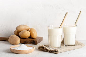 Powdered vegan potato milk in two glasses on neutral backdrop. Selective focus.