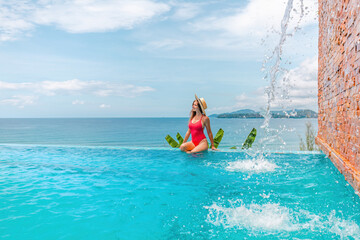 Vacation woman in swimwear relax in the pool. Girl relaxing sunbathing and enjoying her tropical exotic holidays in the resort pool with waterfall splash. Luxury hotel lifestyle.