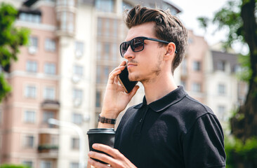 Attractive young man in sunglasses talking on a smartphone in the city.