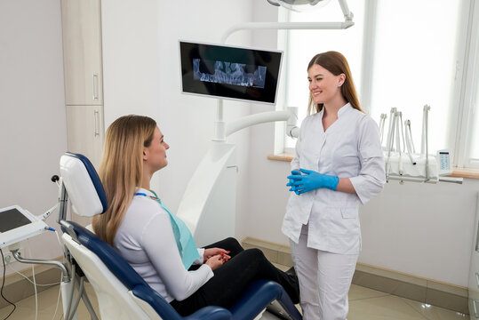 She is sitting in the dentist's chair. The dentist explains and advises the patient.