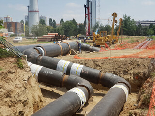 Laying heating pipes in a trench at construction site. - 514815105
