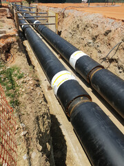 Laying heating pipes in a trench at construction site.