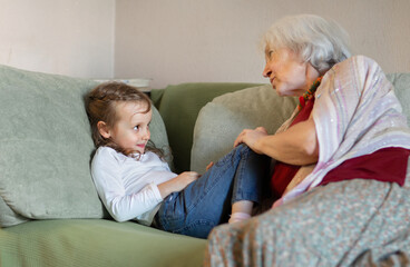 A grandmother tells her granddaughter a fairy tale on the sofa