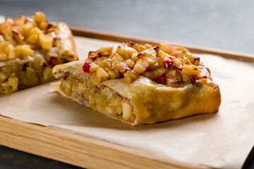 Apple strudel on wooden board on grey table macro close up