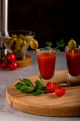 Shorts with alcoholic drink Bloody Mary. Olives and a pepper grinder are in the background.