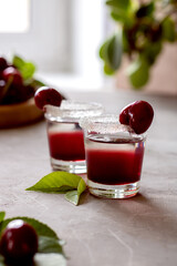 Two shots with cherry alcoholic drink. Decorated with cherries.