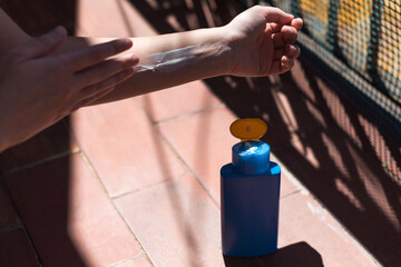 Detalle de una mujer aplicándose protector solar en el brazo en un día soleado. Concepto de protegerse de la exposición al sol en verano.