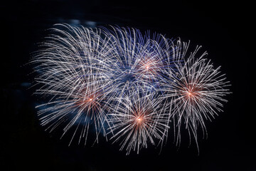 Explosions of pyrotechnics against black night sky. Bright rays of light from festive fireworks.