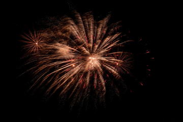 Bright festive fireworks against  black night sky. Flashes and colorful rays of light in dark.