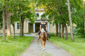 Woman rider riding on the country house yard.