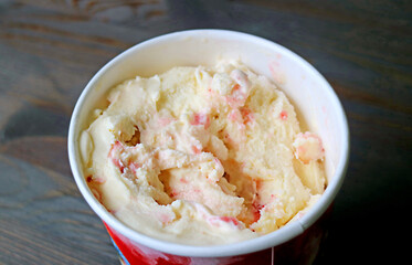 Delectable strawberry-banana ice cream in a big cup on black wooden table
