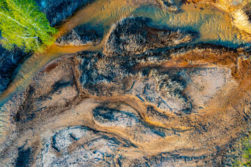 Acid rivers flowing from an industrial copper mine pollute the environment. Orange soil is contaminated with heavy metals from an industrial plant. Aerial view.