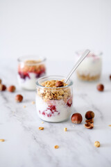 Oatmeal Granola with greek yogurt and nuts strawberry muesli in jars on light background