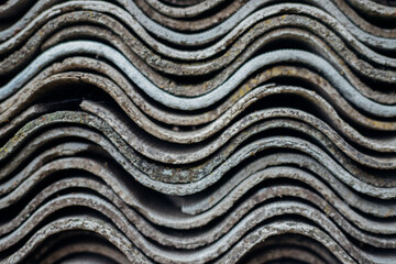 Stacked slate sheets on top of each other. Corrugated asbestos cement sheets.The texture of wavy slate. Building materials. Background.