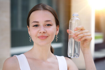 Portrait of beautiful teenager pretty girl, young happy thirsty woman is drinking pure fresh water...