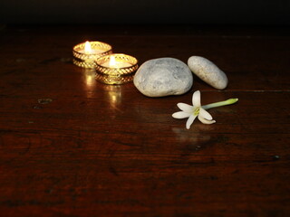 Romantic spa -  massage stones and flowers in candle light on wooden background with copy space. 
Beauty treatment concept. banner copy space. Relaxing concept.