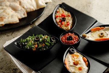 Mixed Mazzaa ssorted breakfast Tabouleh Salad, Hummus, and bread served in a dish isolated on grey background side view fast food
