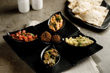 Assorted breakfast Tabouleh Salad, Ful Medames, Vegetable omelet, Scrambled egg with cheese, Macaroni with cheese ball and bread served in a dish isolated on grey background side view fast food