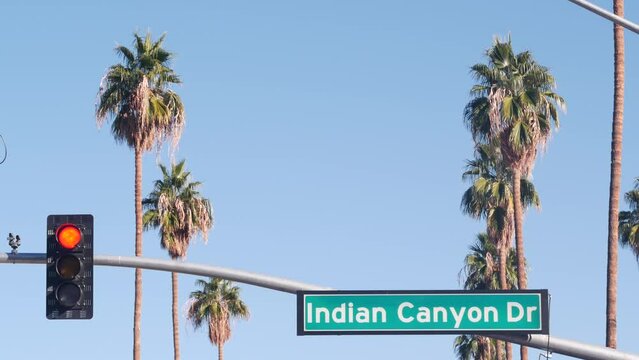Palm trees and blue sky, Palm Springs resort city near Los Angeles, street road sign, semaphore traffic lights on crossroad. California desert valley summer road trip on car, travel USA. Indian Canyon