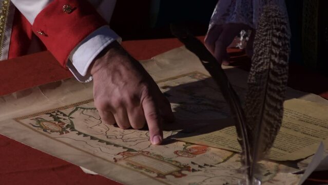 Hands of vintage characterized military generals pointing to an old map in a historical reenactment, Macharaviaya, Spain