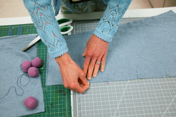 Woman's hands pinning pins into fabric on a table - Powered by Adobe