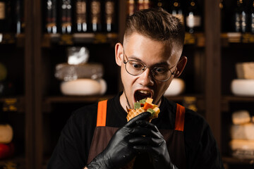 Creative photo of mix of cheeses in waffle cup. Handsome man with mix of young Gouda, young goat, lavander cheese, green and red pesto in waffle cup. Creative idea for advertising a cheese shop.