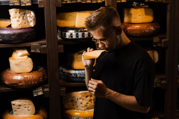 Handsome buyer in cheese shop sniff and enjoy limited gouda cheese. Snack tasty piece of cheese for appetizer.