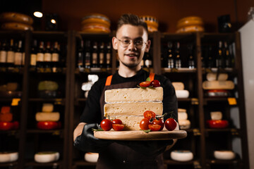 Cheese Sommelier holding plate with brie cheese with tomatoes. Creative idea for advertising a cheese shop.