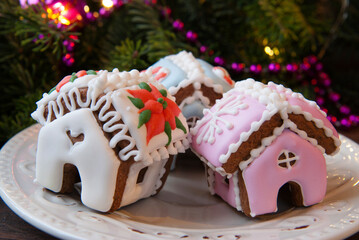 Gingerbread houses with white and pink icing on the background of the christmas tree