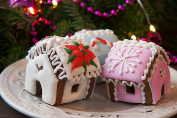 Gingerbread houses with white and pink icing on the background of the christmas tree