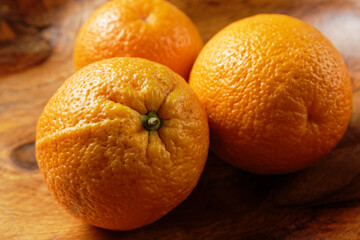 Close up view of three oranges in a wooden bowl