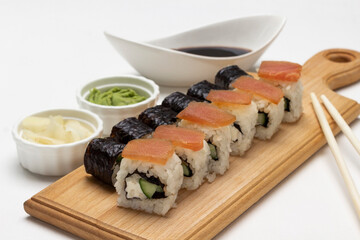 Sushi nori and sushi rolls with salmon on the board.