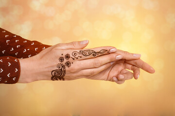 Woman with henna tattoo on hand against blurred background, bokeh effect
