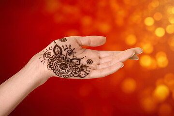 Woman with henna tattoo on palm against blurred lights, bokeh effect