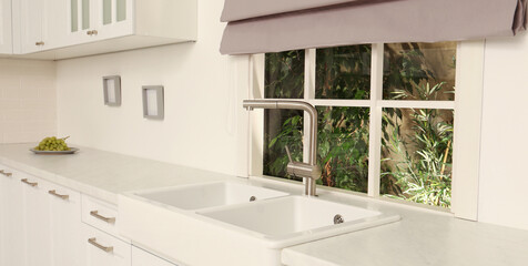 Fototapeta na wymiar White sink with tap near window in kitchen. Interior design