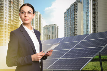 Young businesswoman with tablet near solar panels and beautiful view of cityscape. Alternative...