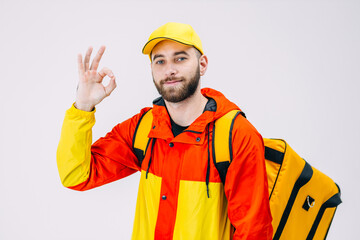 Young bearded man holding a take-away backpack makes an OK sign