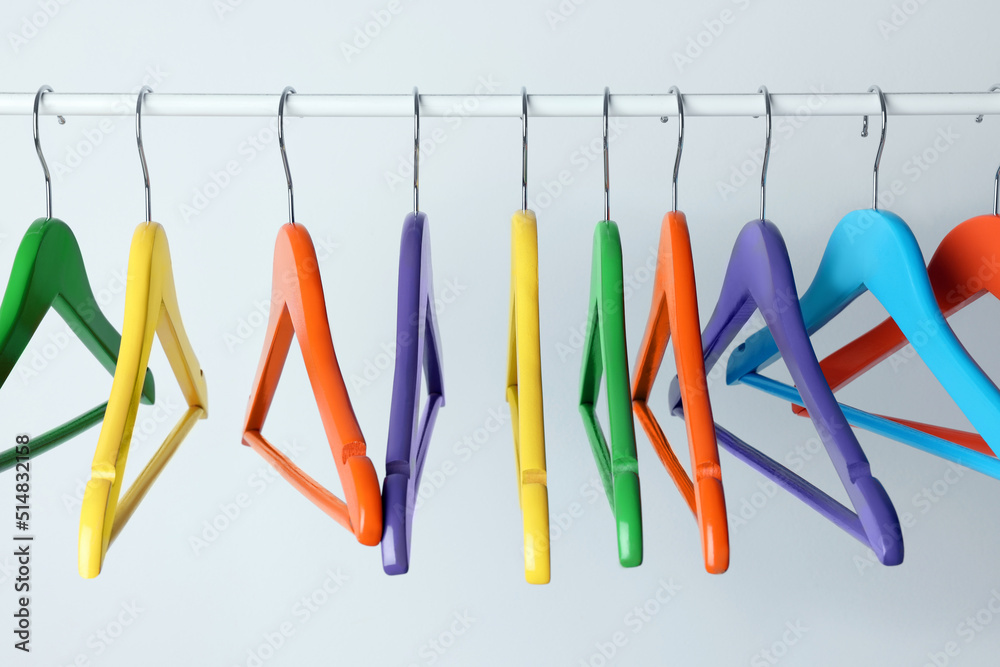 Wall mural Bright clothes hangers on metal rail against light background - Wall murals
