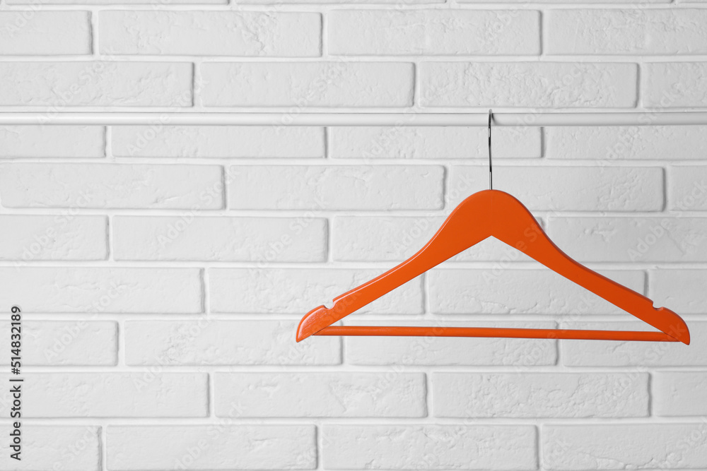 Sticker Orange clothes hanger on rail near white brick wall. Space for text - Stickers