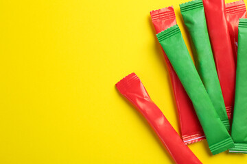 Different sticks of sugar on yellow background, flat lay. Space for text