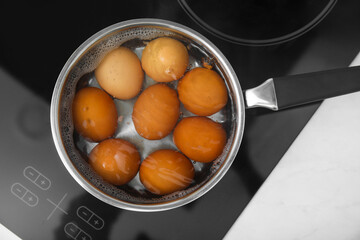 Boiling chicken eggs in saucepan on electric stove, top view