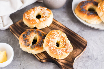 Bagels with poppy seeds and sesame on the board and butter in a bowl. Homemade breakfast